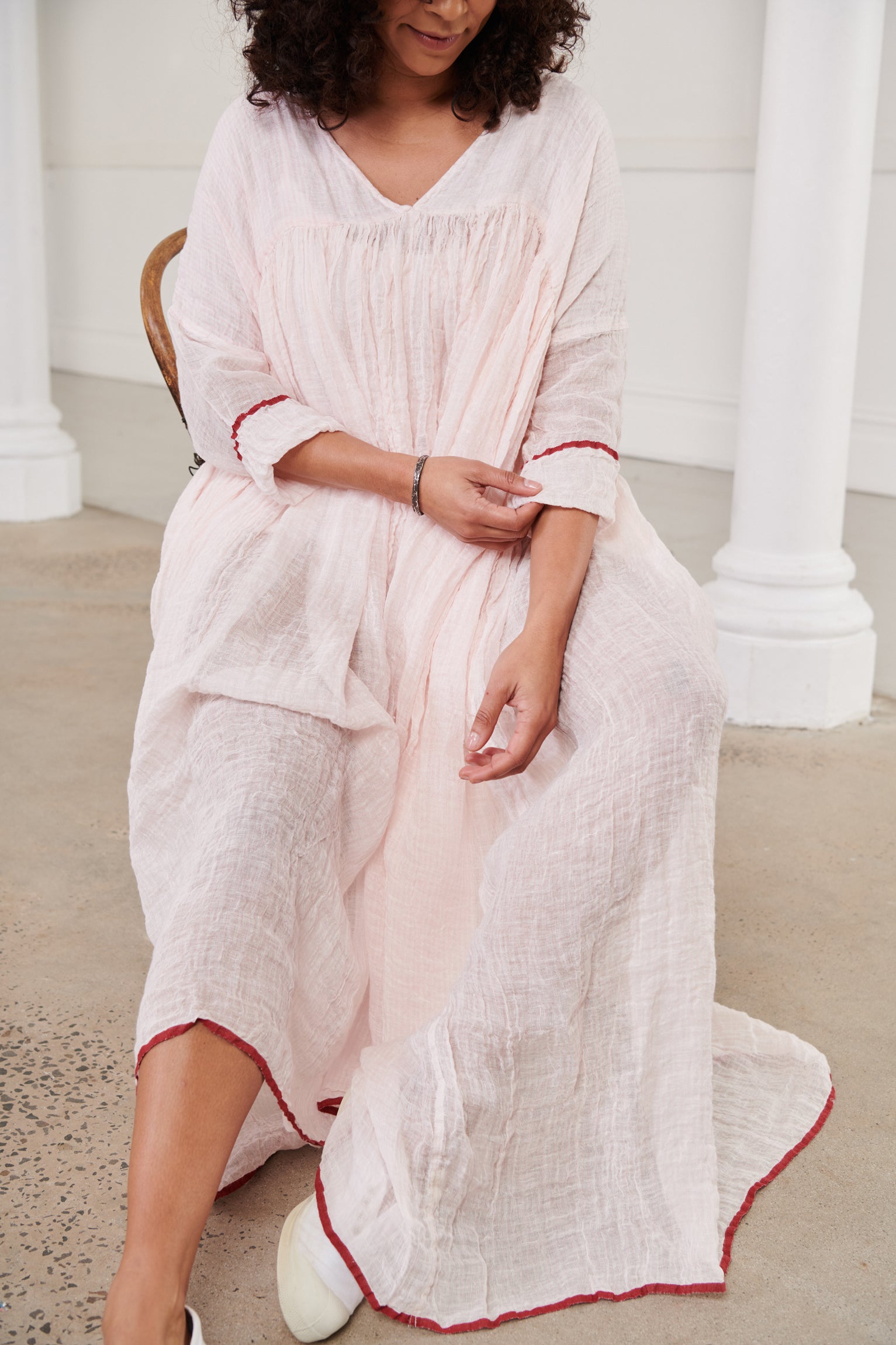 A MegbyDesign model is wearing a pink soft gauze linen tunic dress with a red trim