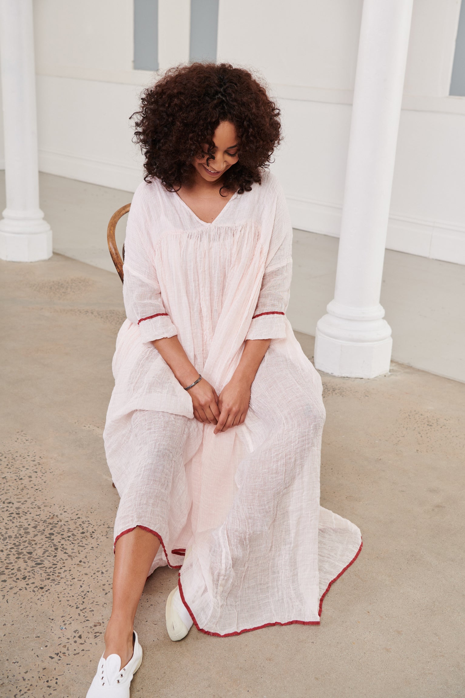 A MegbyDesign model is wearing a pink soft gauze linen tunic dress with a red trim