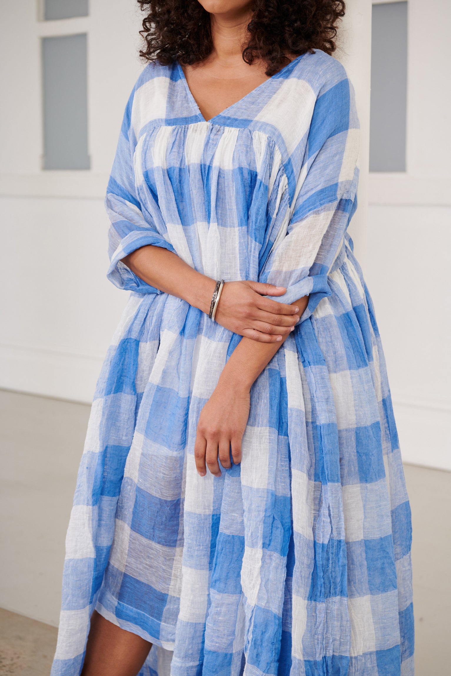 A MegbyDesign model is wearing a blue and white gingham soft gauze linen tunic dress