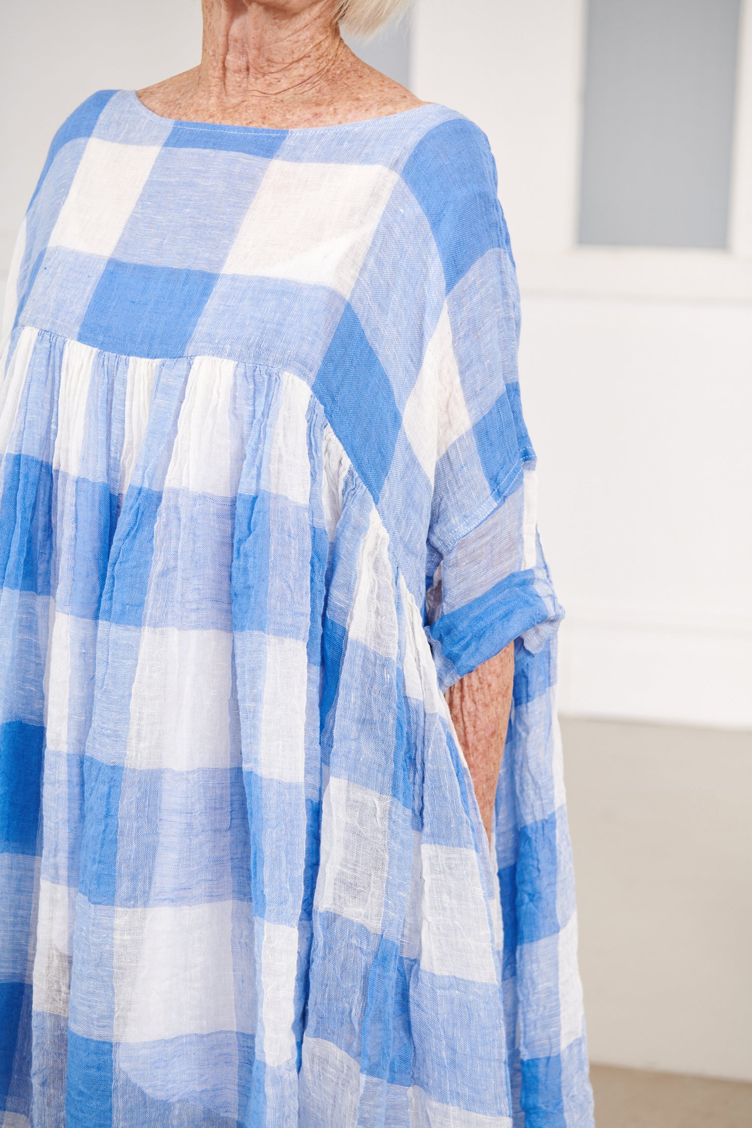 A MegbyDesign model is wearing a blue and white gingham soft gauze linen tunic dress