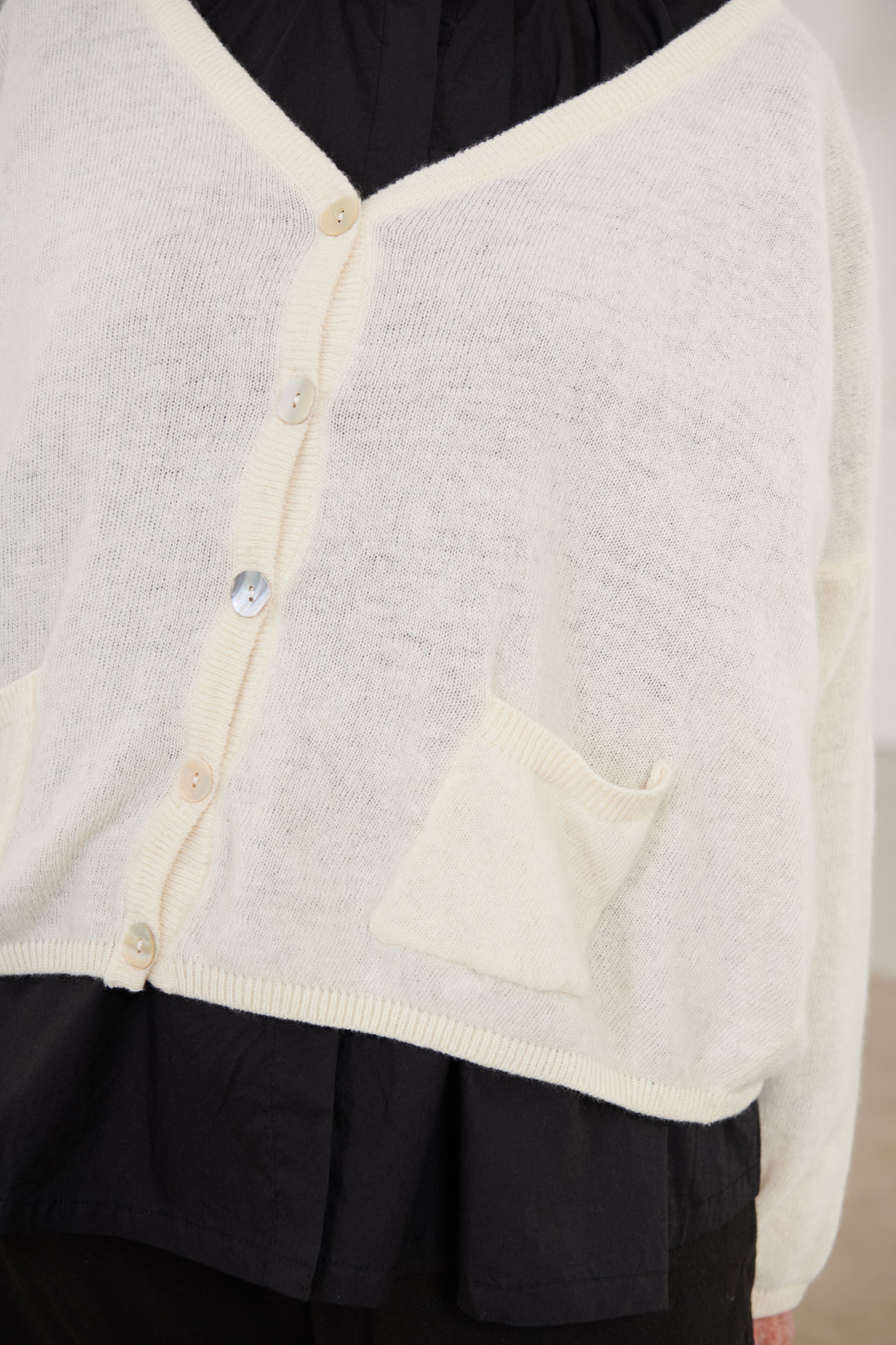 A MegbyDesign model is wearing a cream oversized wool cardigan with two pockets and buttons at the front