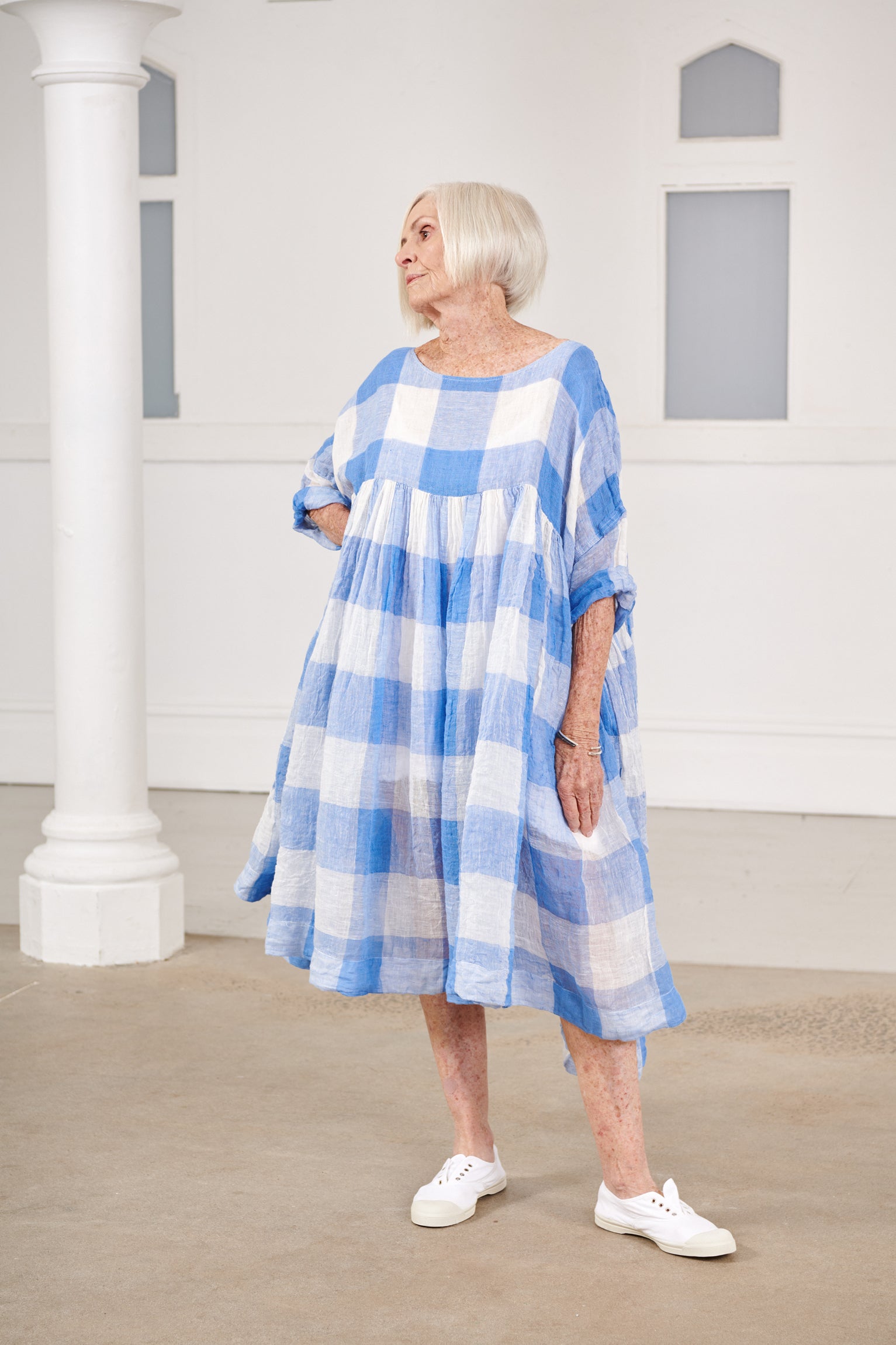 A MegbyDesign model is wearing a blue and white gingham soft gauze linen tunic dress