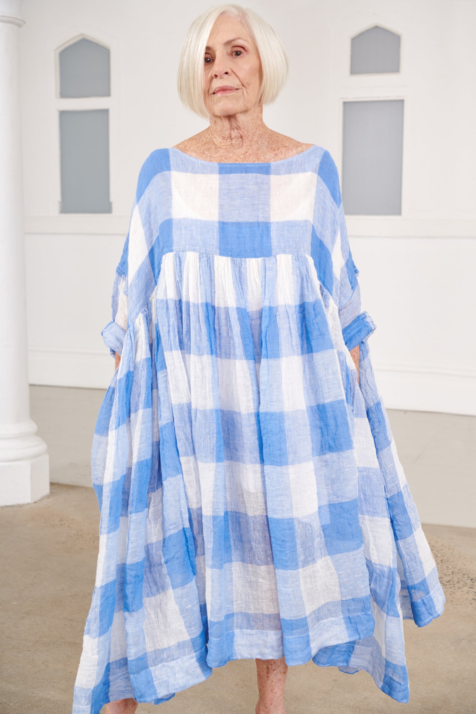 A MegbyDesign model is wearing a blue and white gingham soft gauze linen tunic dress