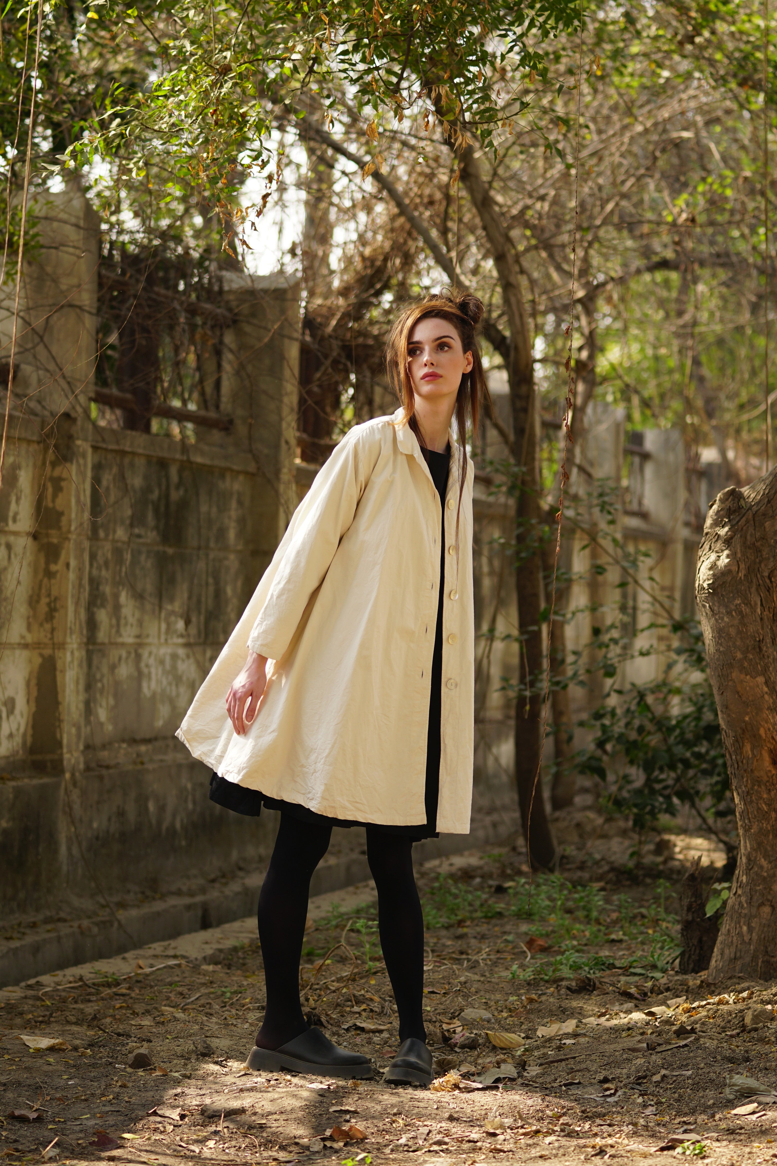 A MegbyDesign model is wearing a lined cotton twill cream coat with large black spots featuring agoya shell buttons, side pockets and a classic cut collar