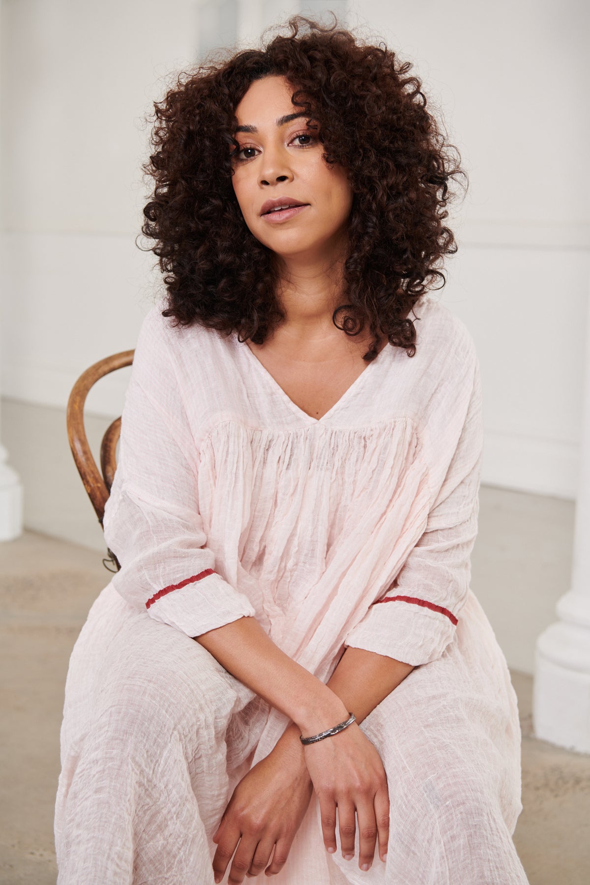 A MegbyDesign model is wearing a pink soft gauze linen tunic dress with a red trim