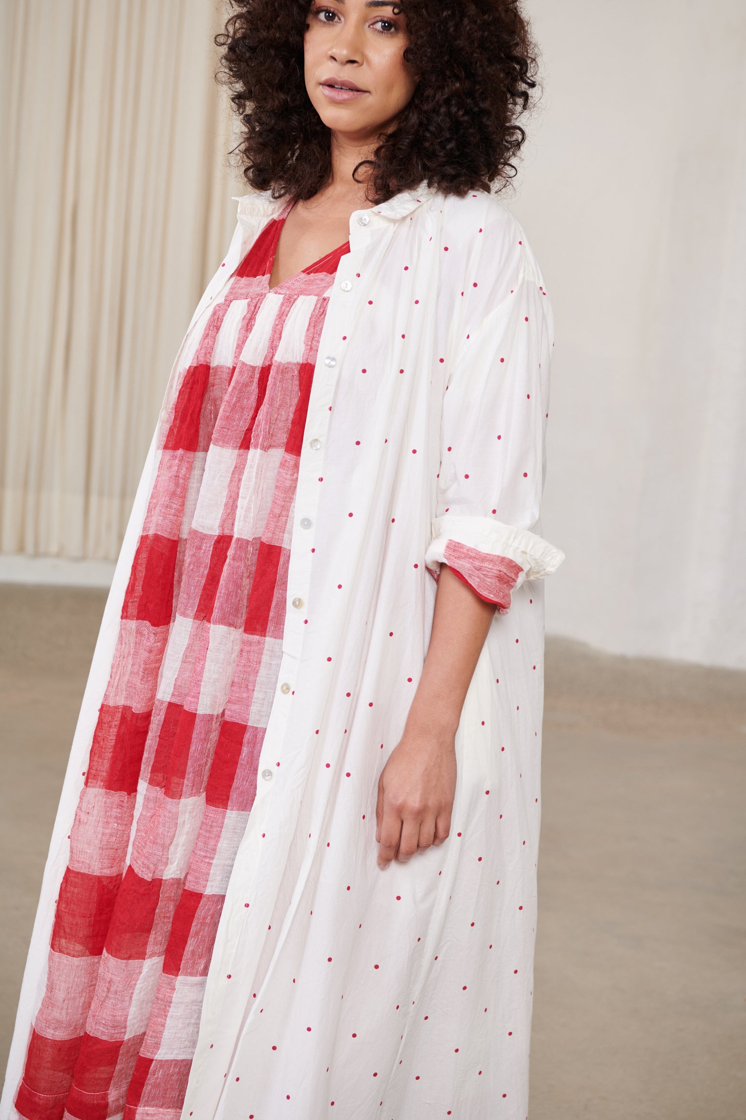 A MegbyDesign model is wearing a white ankle length button down style shirt in a paper cotton material with red spots