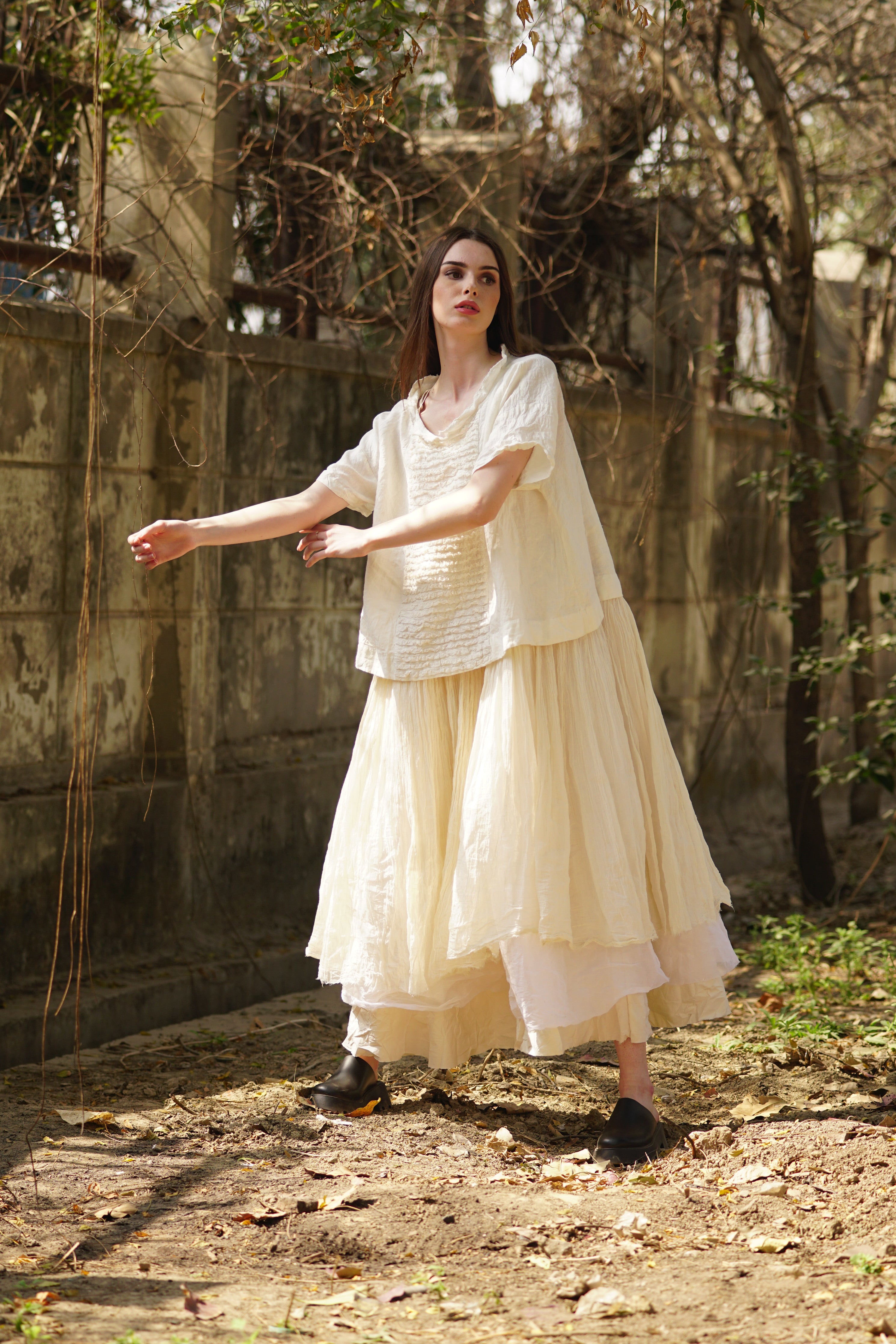 A MegbyDesign model is wearing a cream three layered tutu slip made with cotton twill, cotton organdy and cotton gauze raw hem skirt. 
