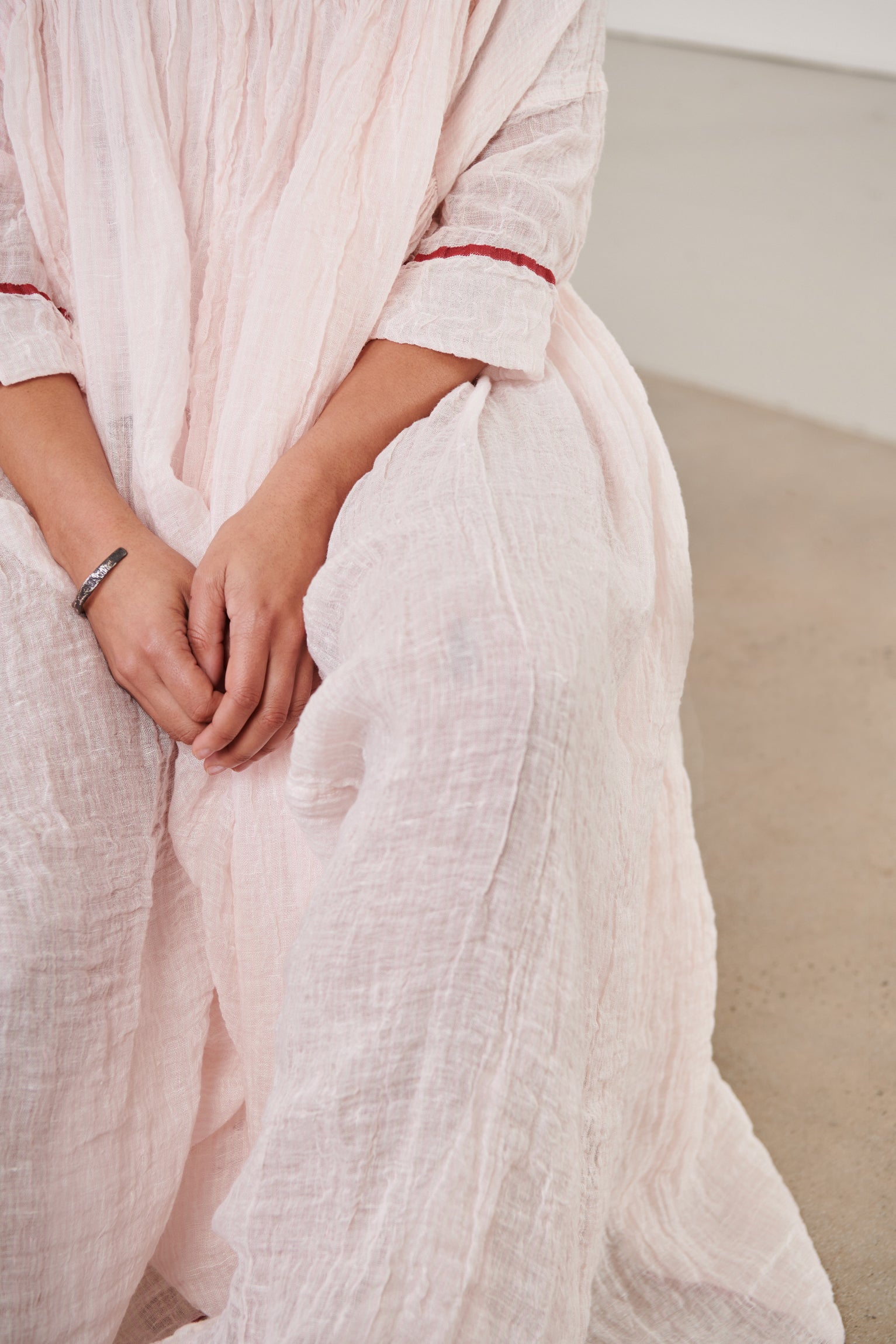 A MegbyDesign model is wearing a pink soft gauze linen tunic dress with a red trim