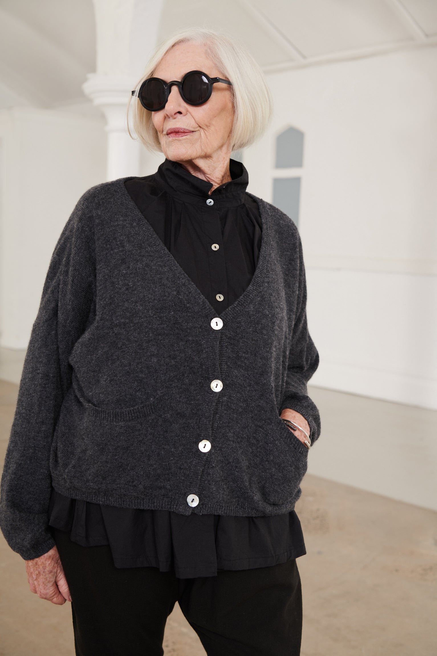 A MegbyDesign model is wearing a charcoal oversized wool cardigan with two pockets and buttons at the front