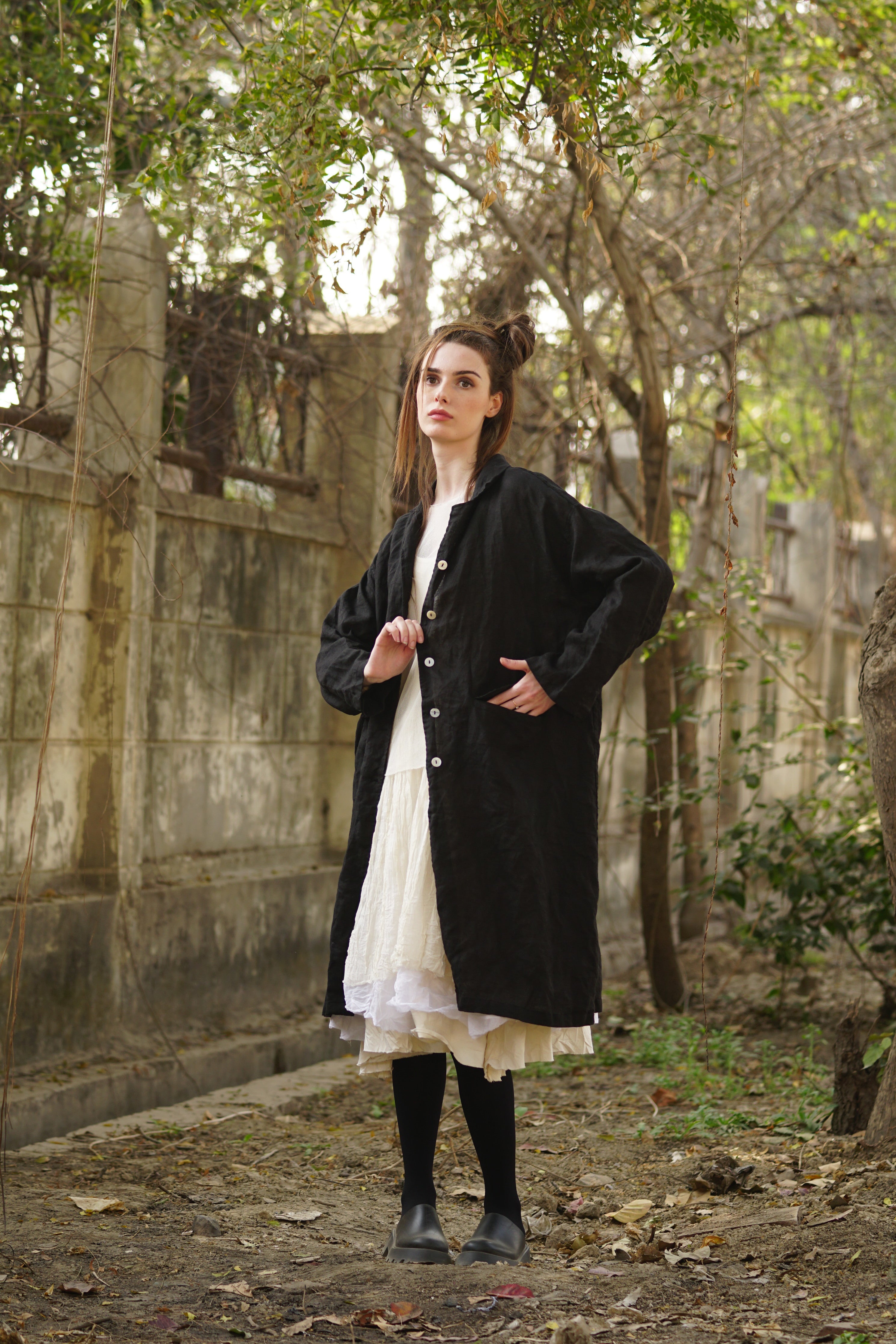 A MegbyDesign model is wearing a black linen coat with agoya shell buttons