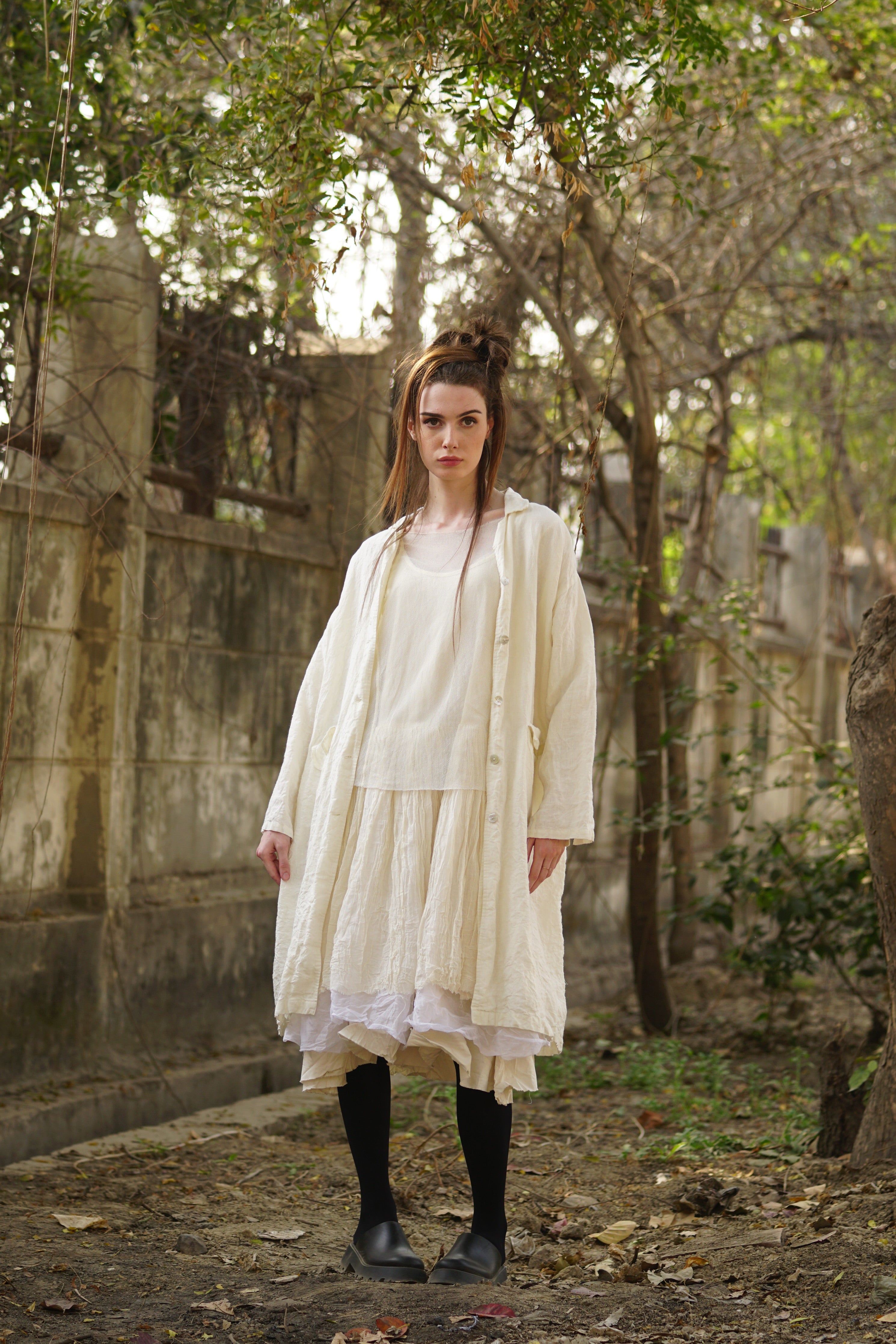 A MegbyDesign model is wearing a cream linen coat with agoya shell buttons